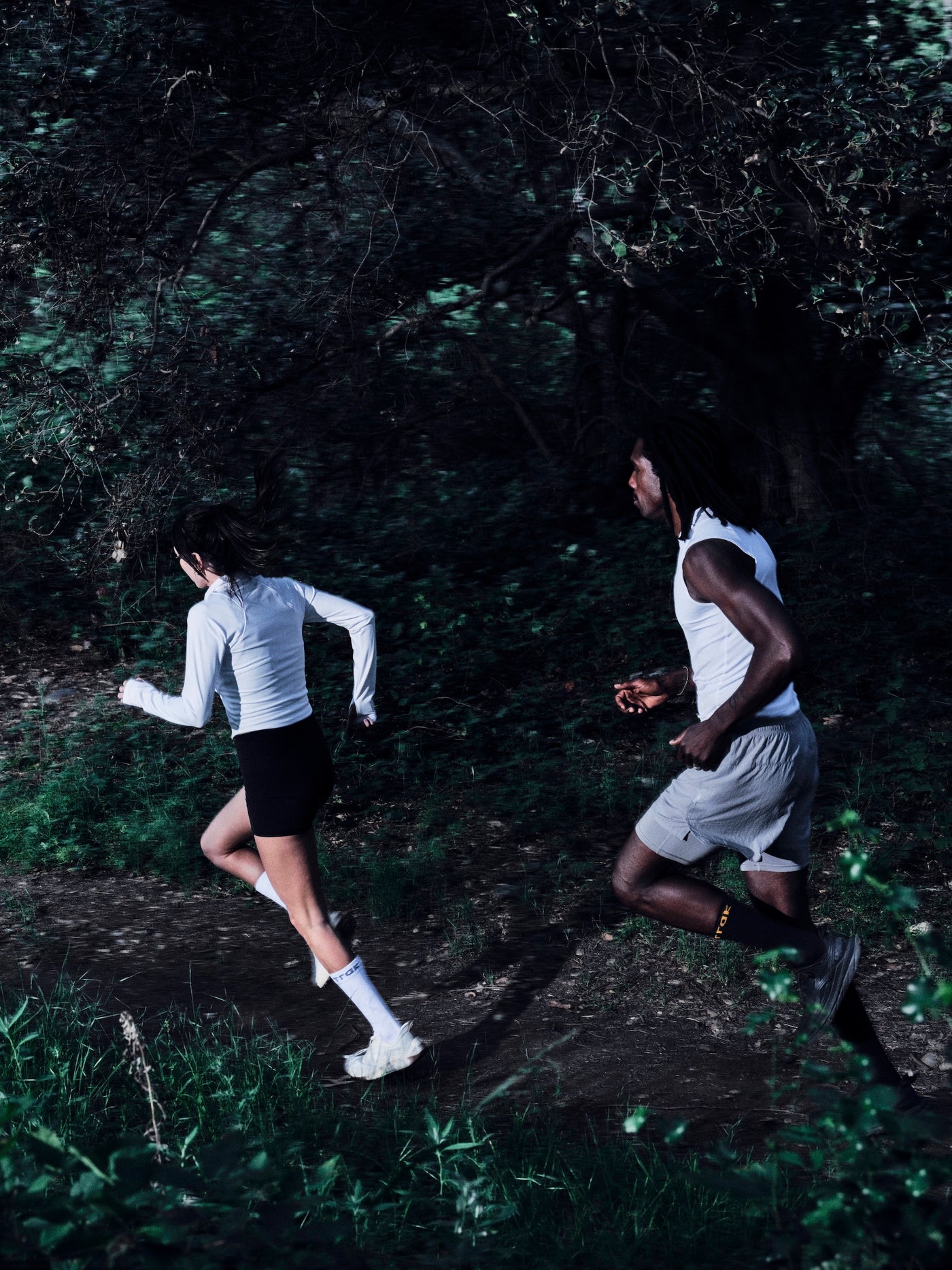 Two people running through a forest path