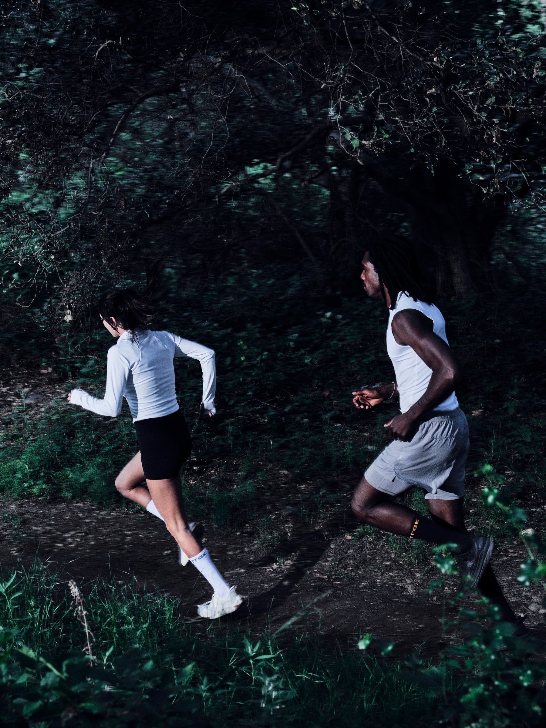Two people running through a forest path